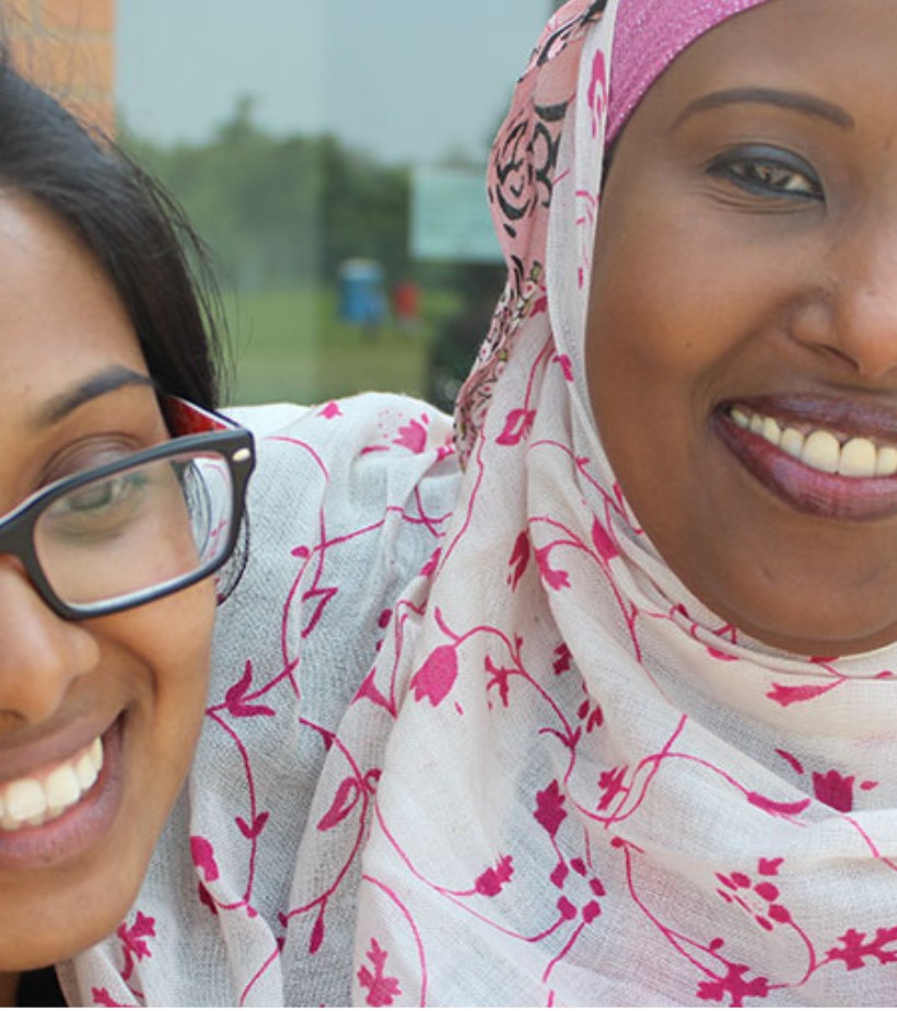 Two women smiling together outside the centre.